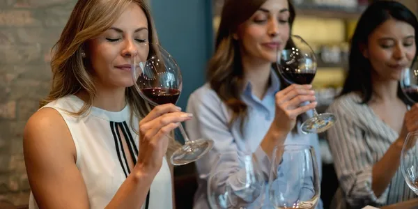 Women tasting red wine at a table.